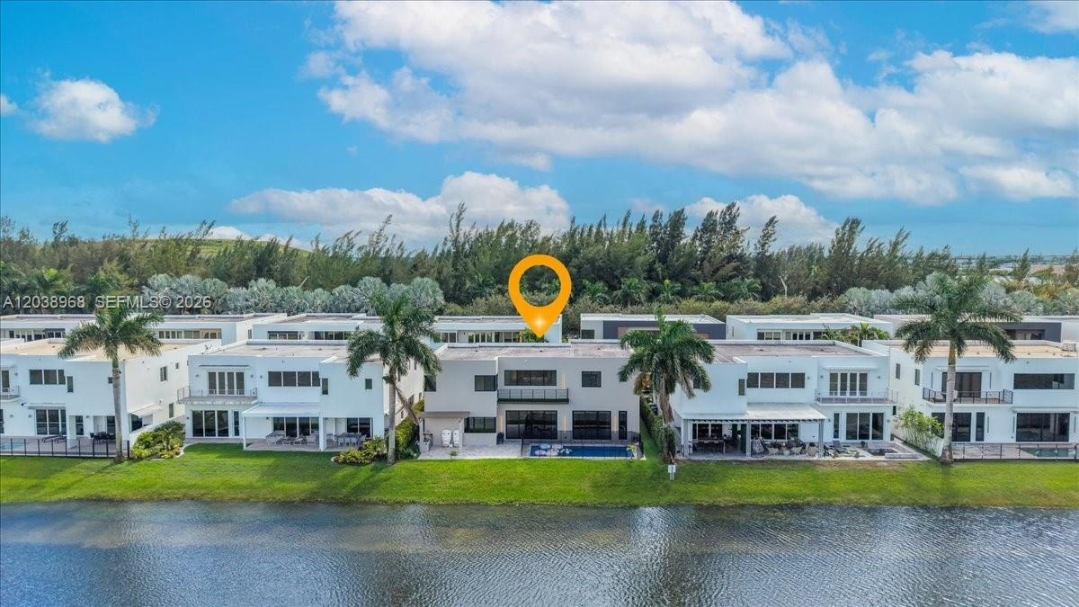 Waterfront residence featuring a modern architectural design, private swimming pool, second-story balcony, and manicured landscaping