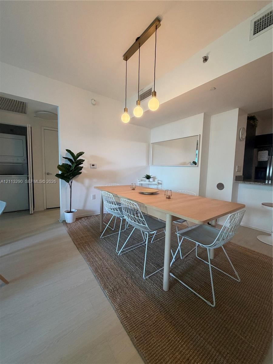 Multi-pendant linear light fixture with exposed bulbs, neutral wood-finish flooring, and wall-mounted mirror
