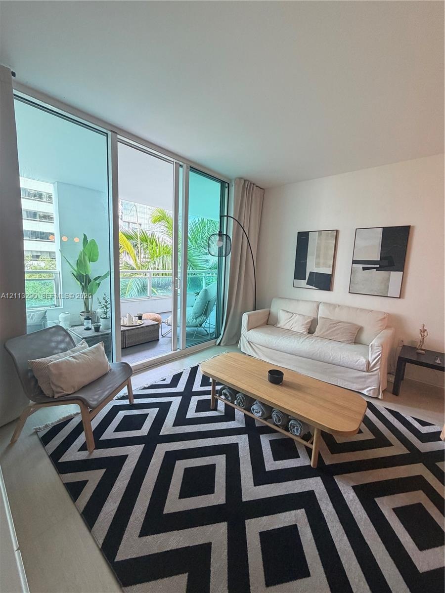Floor-to-ceiling glass sliding doors, private balcony with metal railing, and neutral wall finishes