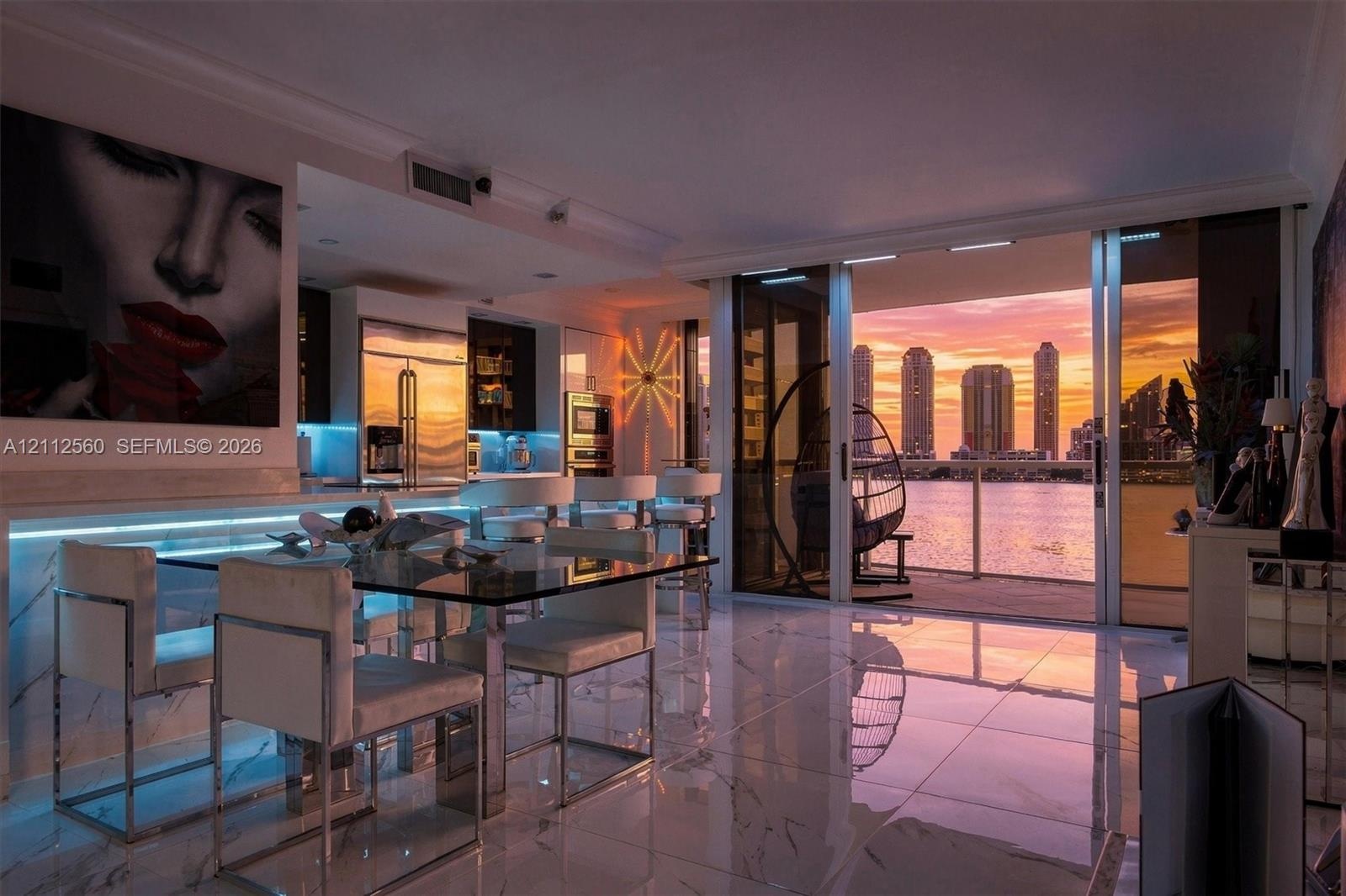 Large-format polished tile flooring, integrated linear LED under-cabinet lighting, stainless steel built-in appliances, and expansive sliding glass do