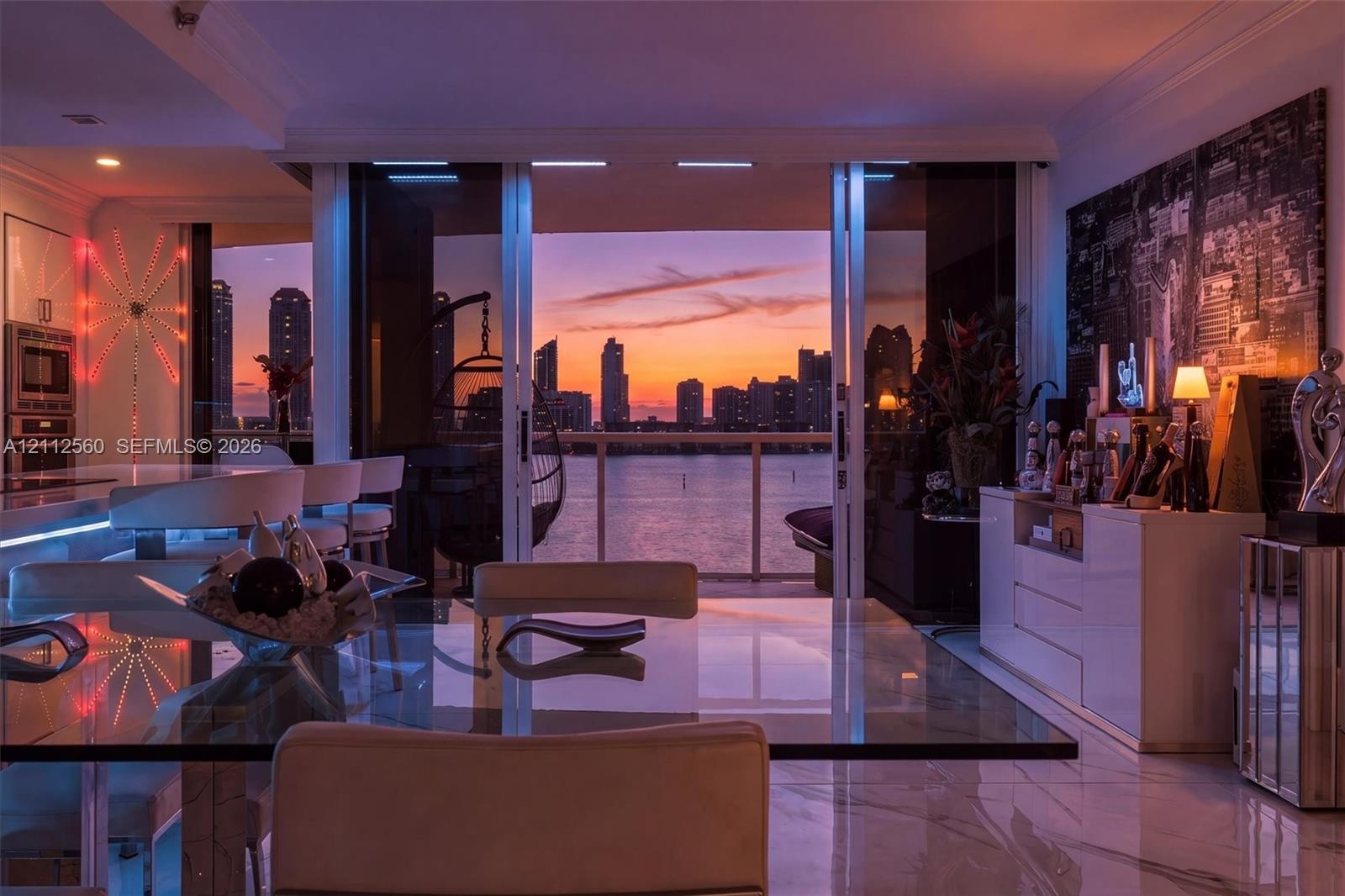 Floor-to-ceiling sliding glass doors, stone-finish flooring, built-in cabinetry, and integrated kitchen appliances, complemented by a water and citysc