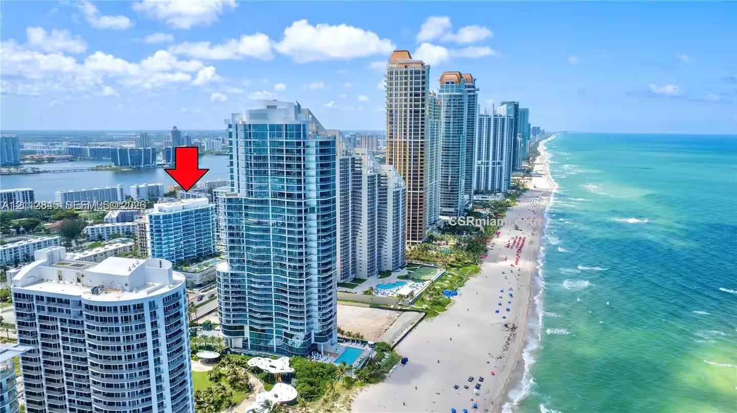 Aerial perspective featuring coastal high-rise structures, direct oceanfront proximity, and sandy beach access