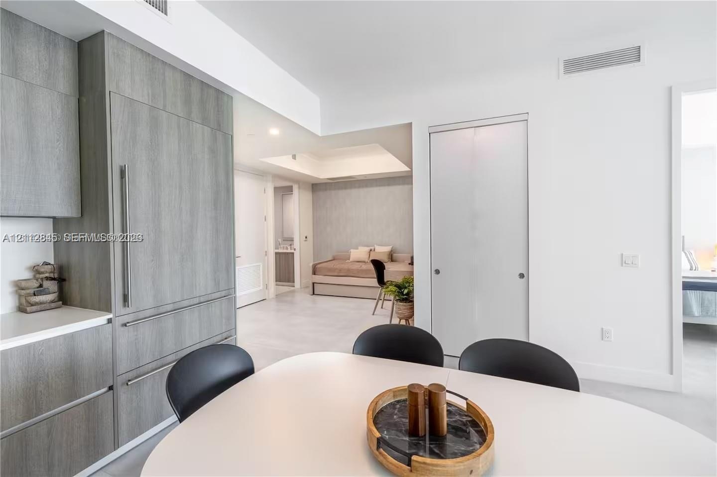 Modern kitchen cabinetry with wood-finish paneling, integrated refrigerator, white stone countertops, and tile flooring