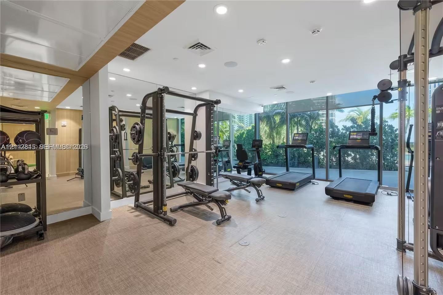 Fitness center featuring floor-to-ceiling windows, full-wall mirrors, recessed lighting, and resilient textured flooring