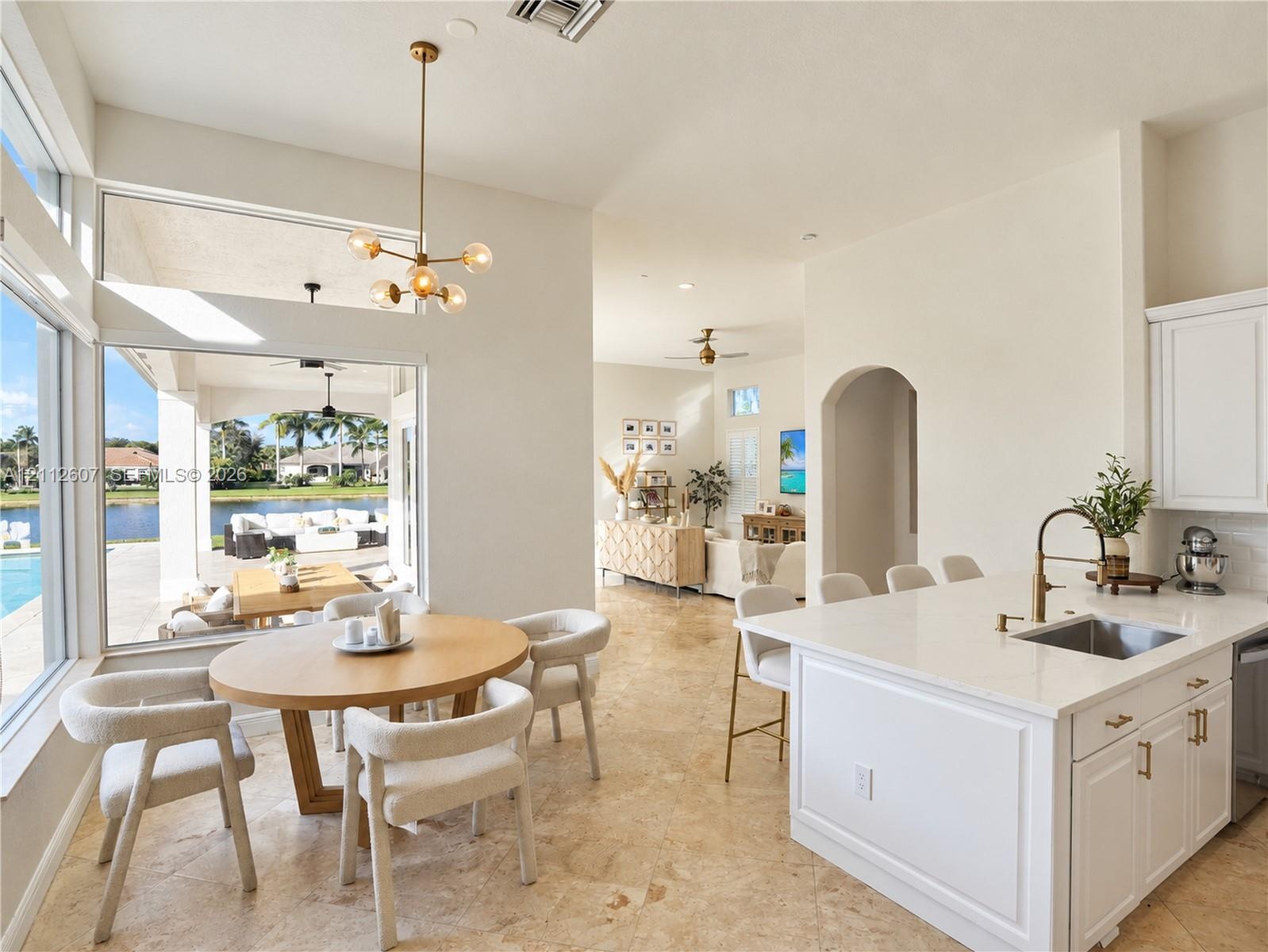 Open-concept kitchen featuring an island with stone-surface countertop, undermount sink, and metallic faucet hardware, complemented by natural stone f