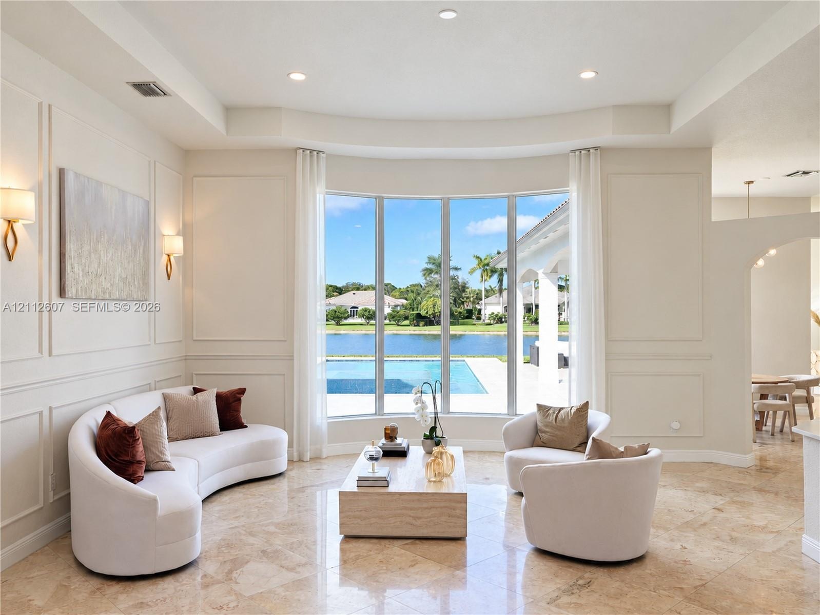 Formal living space featuring a bay window, wall molding, recessed ceiling lighting, wall-mounted light fixtures, and stone flooring