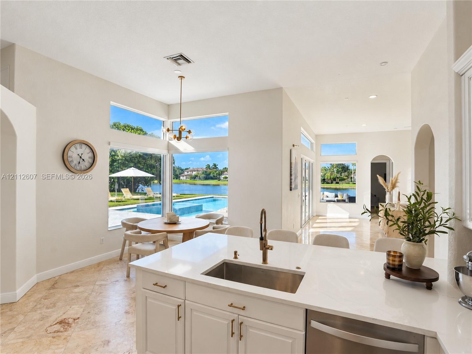 Kitchen featuring stone flooring, white cabinetry, a quartz countertop, an undermount stainless steel sink with a metallic faucet, and expansive floor