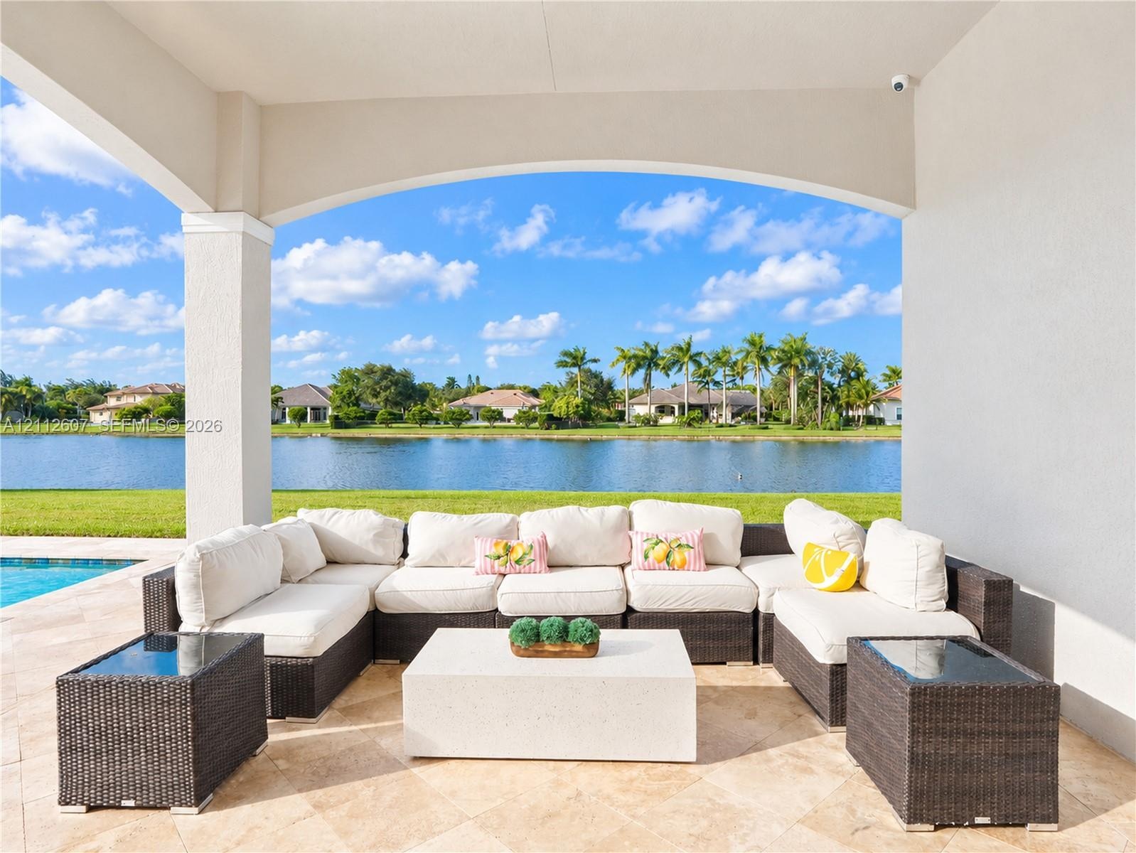Covered lanai featuring natural stone flooring, arched structural detailing, and water frontage