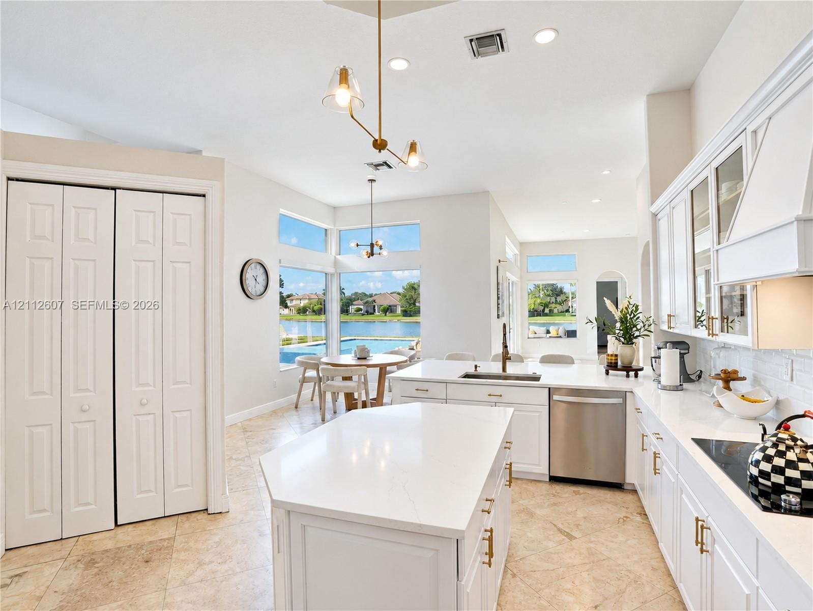 Kitchen featuring white cabinetry, center island with stone-finish countertops, stainless steel appliances, tile flooring, and floor-to-ceiling window