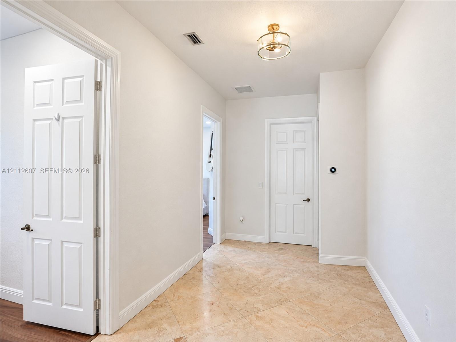 Hallway featuring diagonal-set tile flooring, multi-panel doors, and a decorative drum-style ceiling light fixture