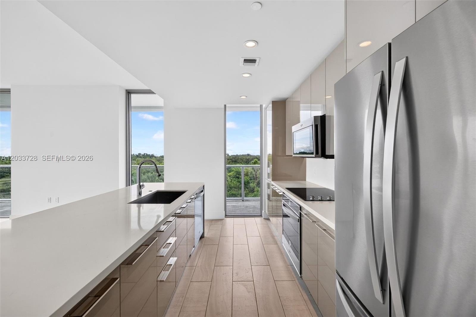 Floor-to-ceiling glass walls, wrap-around balcony with glass railings, ceramic tile flooring, and expansive windows