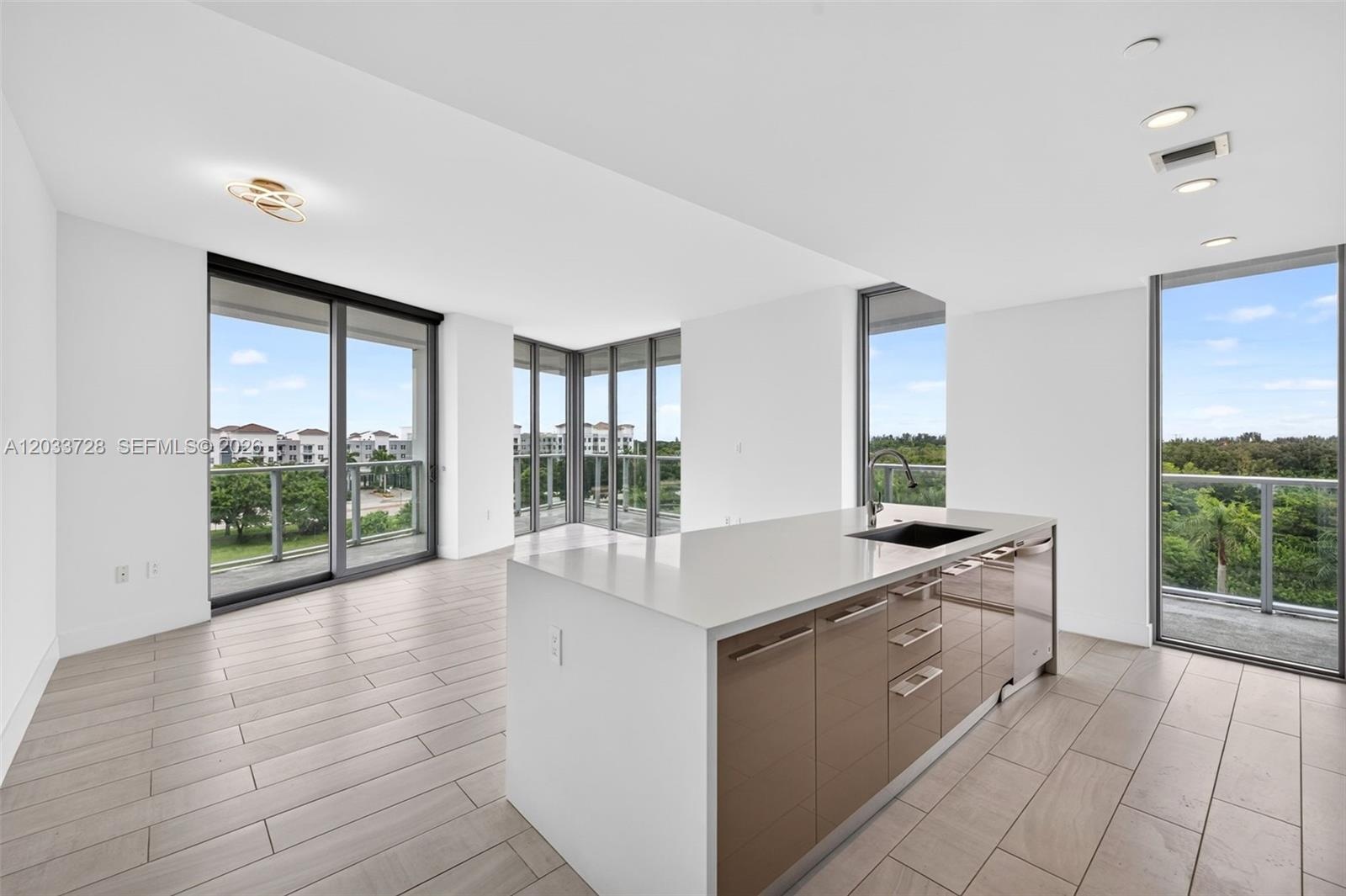 Kitchen island featuring light-toned wood-finish cabinetry, quartz countertops, and an integrated undermount sink with a gooseneck faucet, set against