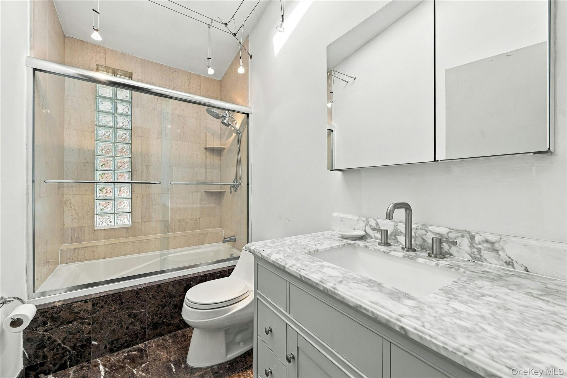 The main-level full hall bath features elegant marble flooring and a skylight that fills the space with natural light.