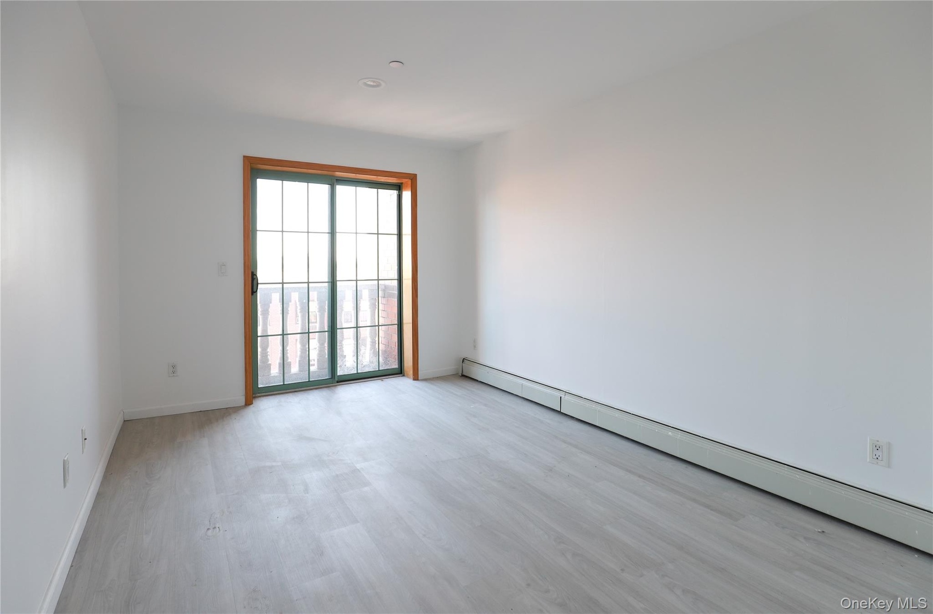 Interior room featuring wood-finish flooring, recessed ceiling lighting, and a sliding glass door with a wood-trim frame