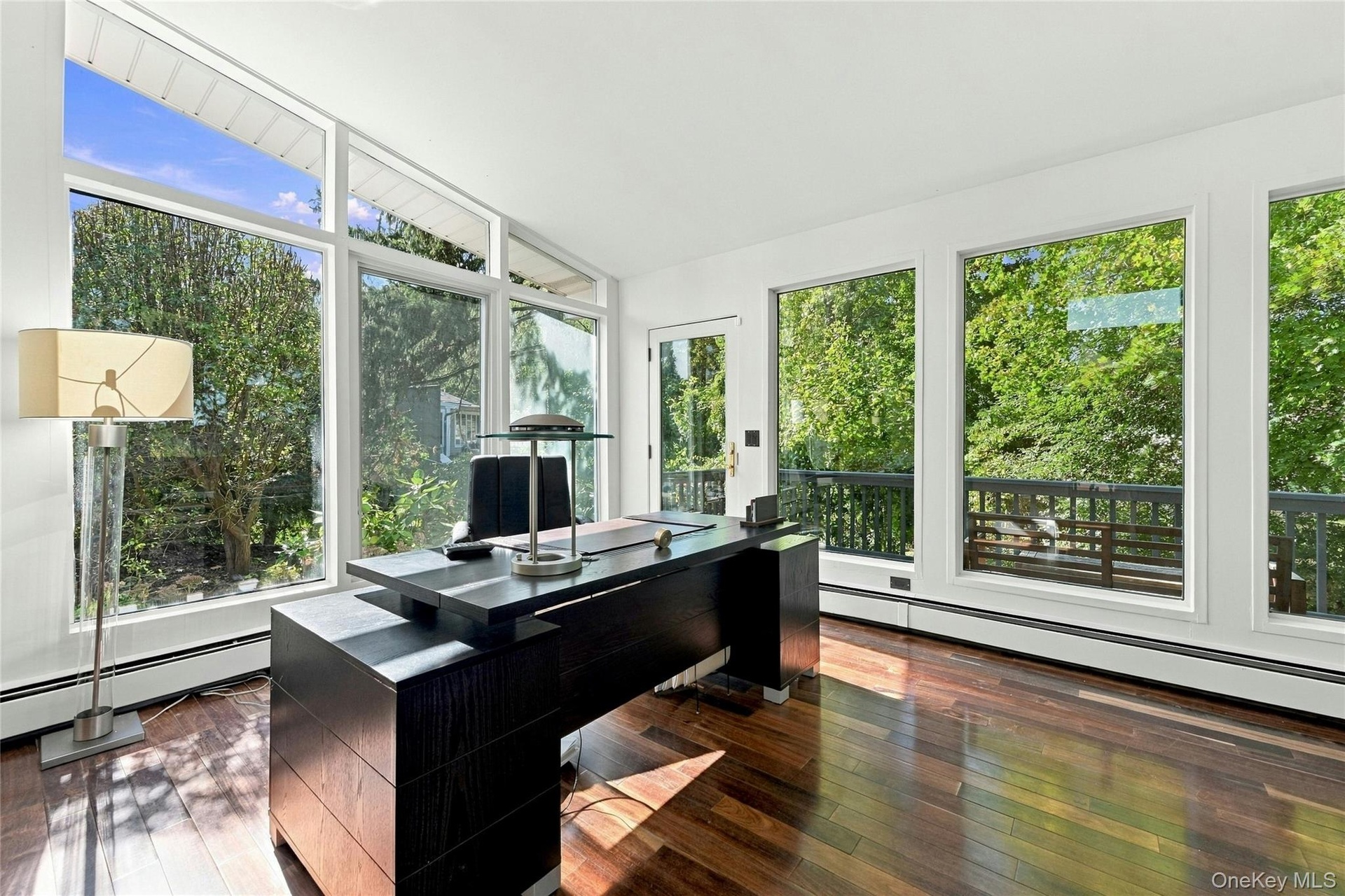 Home office featuring expansive floor-to-ceiling windows, hardwood flooring, and private deck