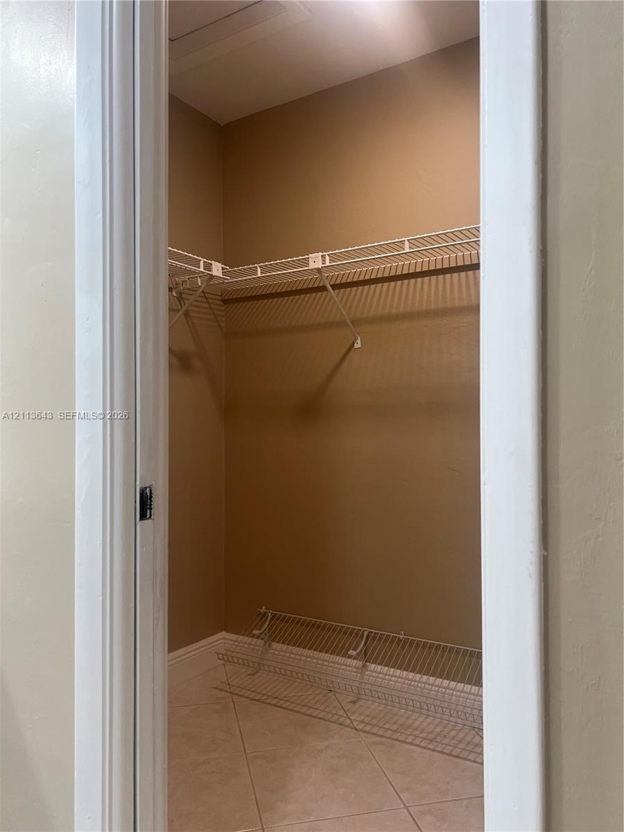 Walk-in closet featuring ceramic tile flooring, neutral wall paint, and multi-level white wire shelving
