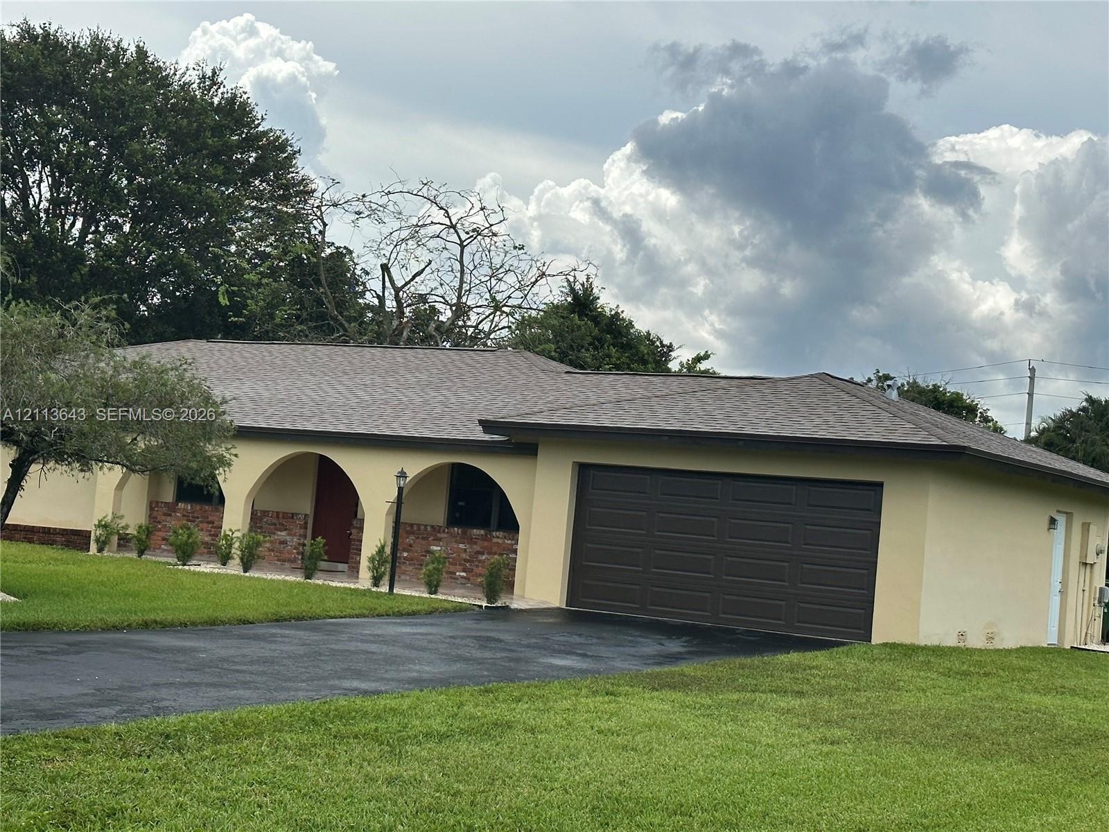 Single-story residence featuring a covered front porch with decorative masonry arches, brick veneer accents, an asphalt-shingle roof, and an attached 