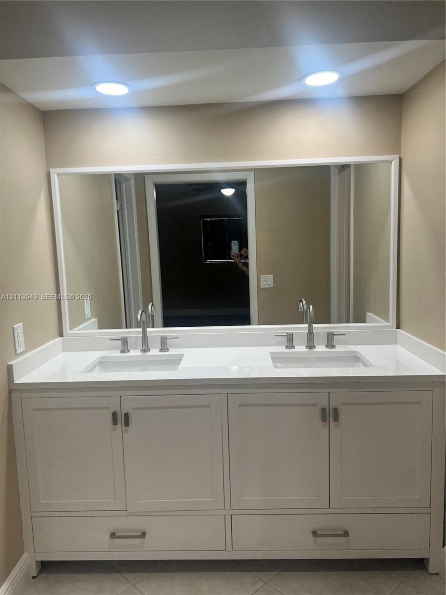 Double vanity featuring white cabinetry, a solid-surface countertop, dual rectangular undermount sinks, polished metal widespread faucets, and a full-