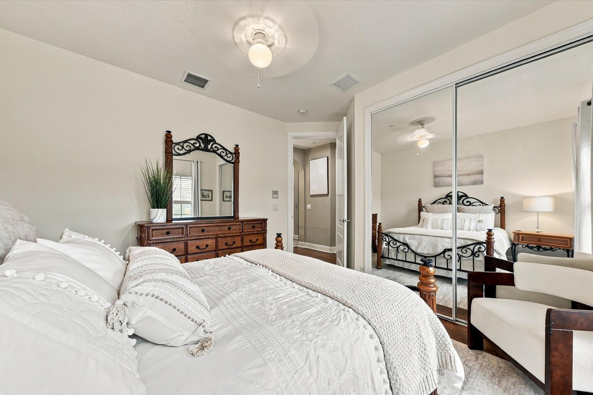 Bedroom interior featuring neutral wall paint, overhead ceiling fan with light fixture, and floor-to-ceiling mirrored sliding closet doors