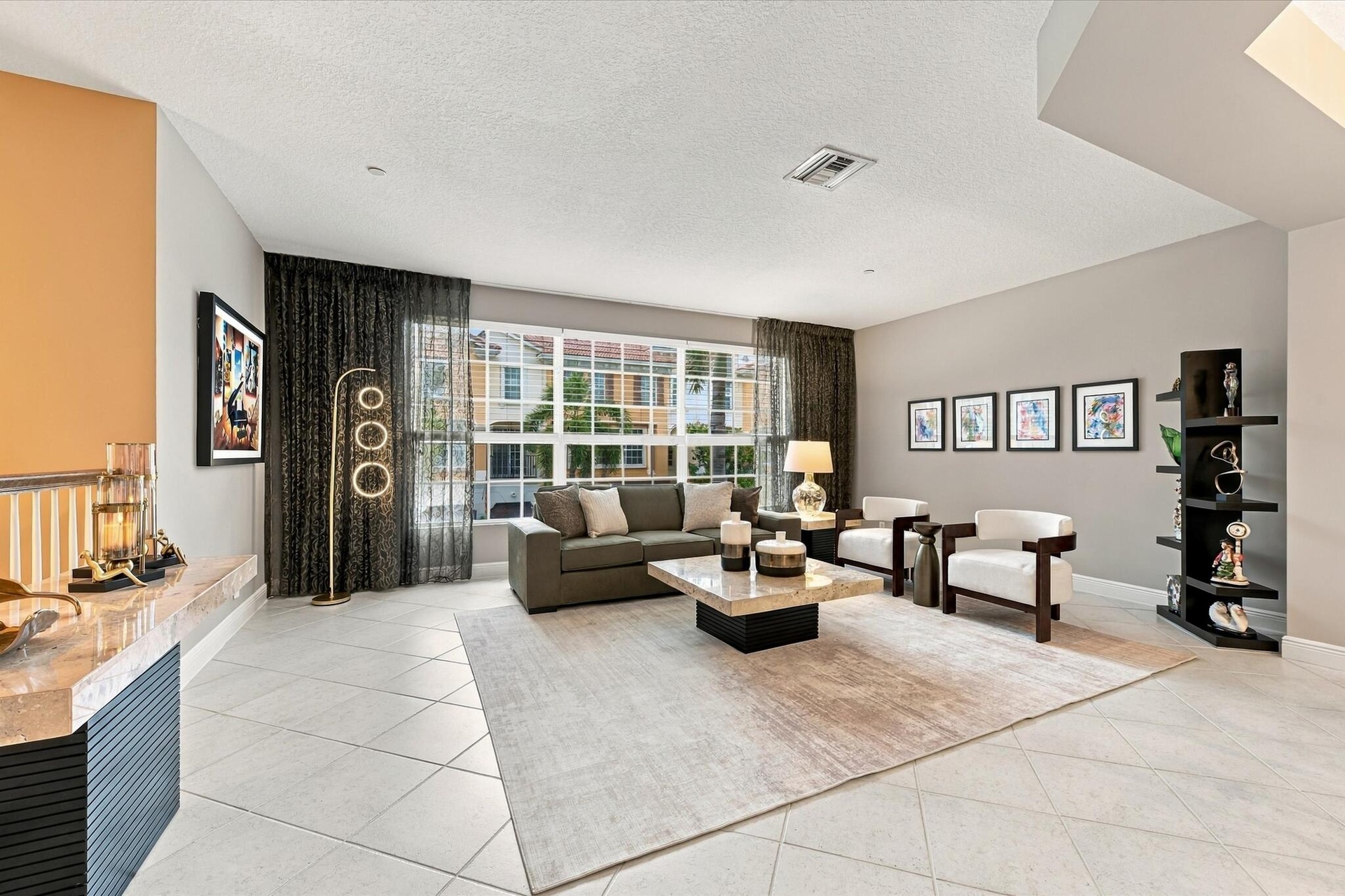 Spacious room featuring light-colored tile flooring, oversized multi-pane windows, neutral wall paint, and a built-in counter surface with stone detai