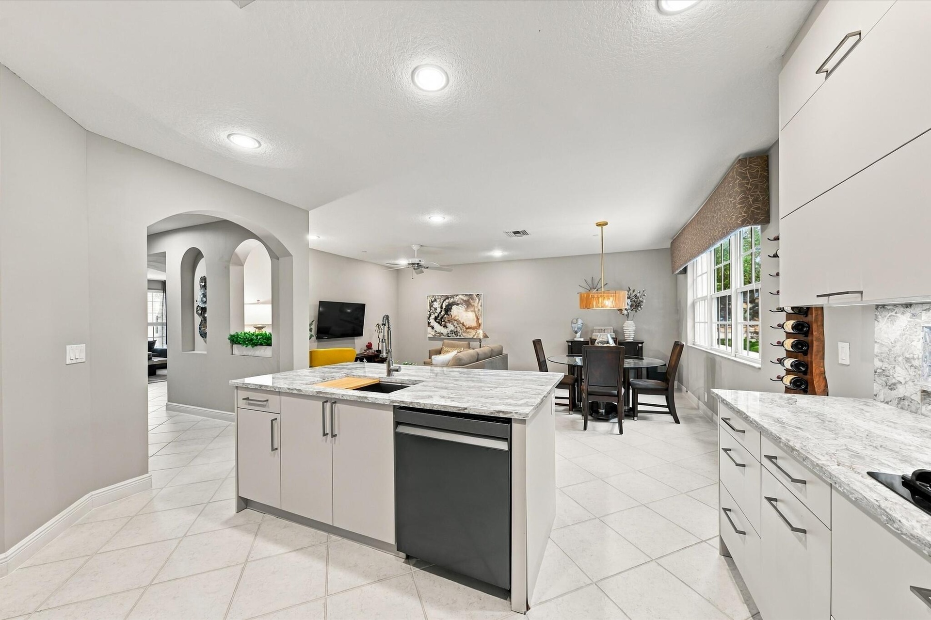 Kitchen featuring light-toned cabinetry, stone-finish countertops, recessed lighting, tile flooring, and a central island with a built-in dishwasher
