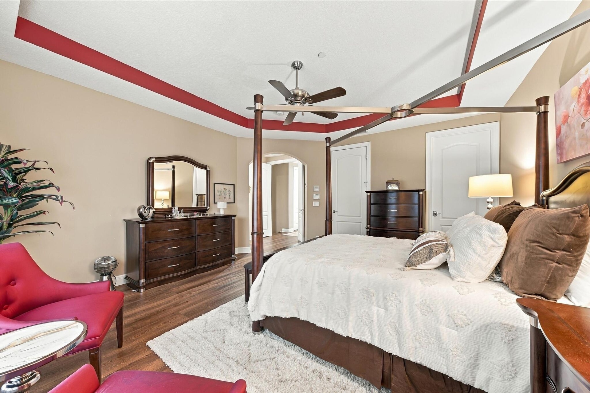 Room featuring tray ceiling with accent molding, wood-finish flooring, and a ceiling fan