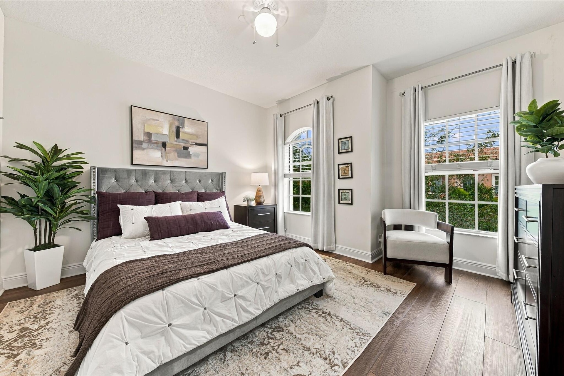 Bedroom featuring wood-finish flooring, an arched window, and a standard rectangular window with multi-pane grids