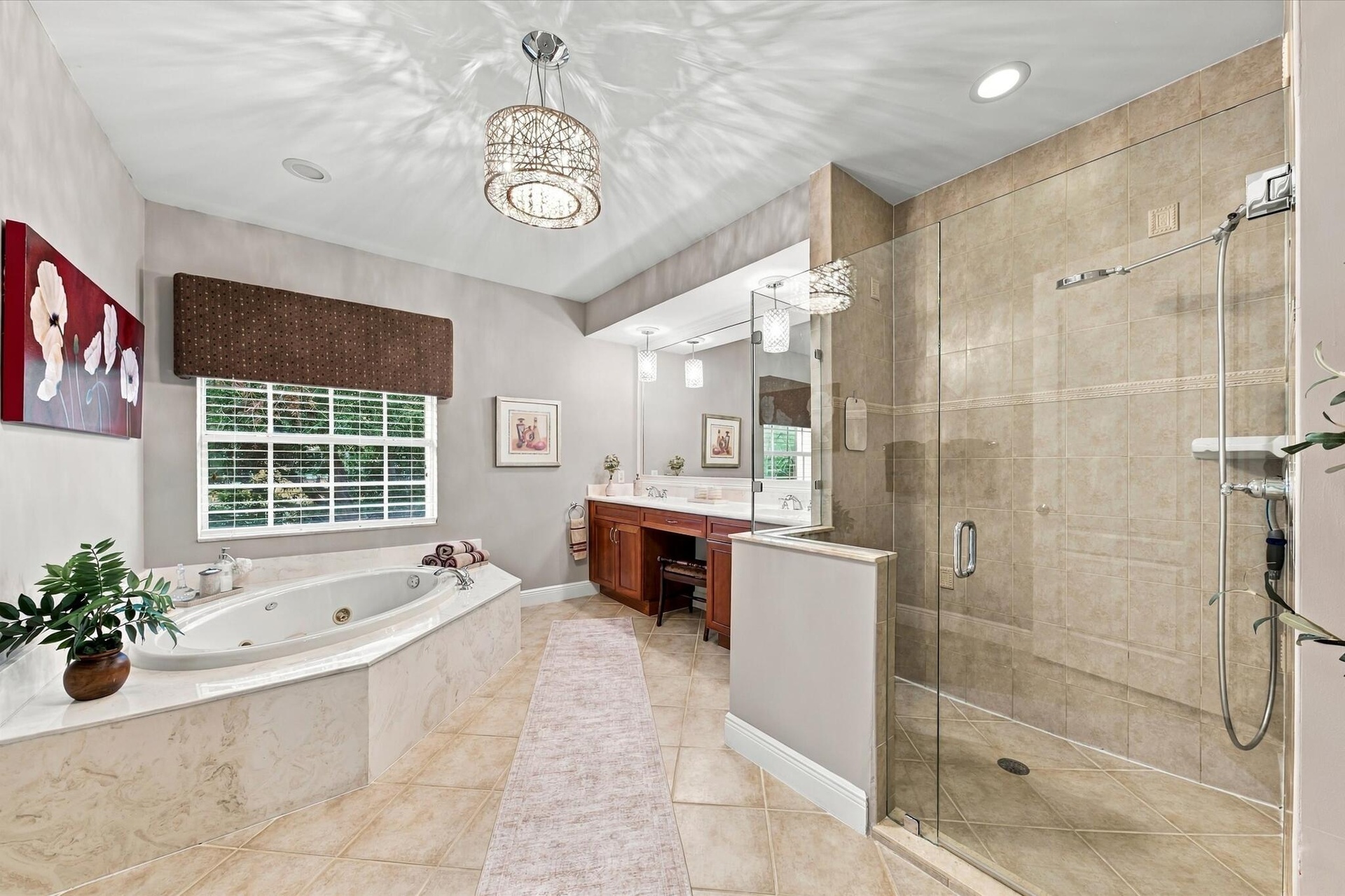 Jetted soaking tub with tile surround, walk-in glass-enclosed shower, dual-sink vanity with built-in cabinetry, crystal-accented light fixture, and ti