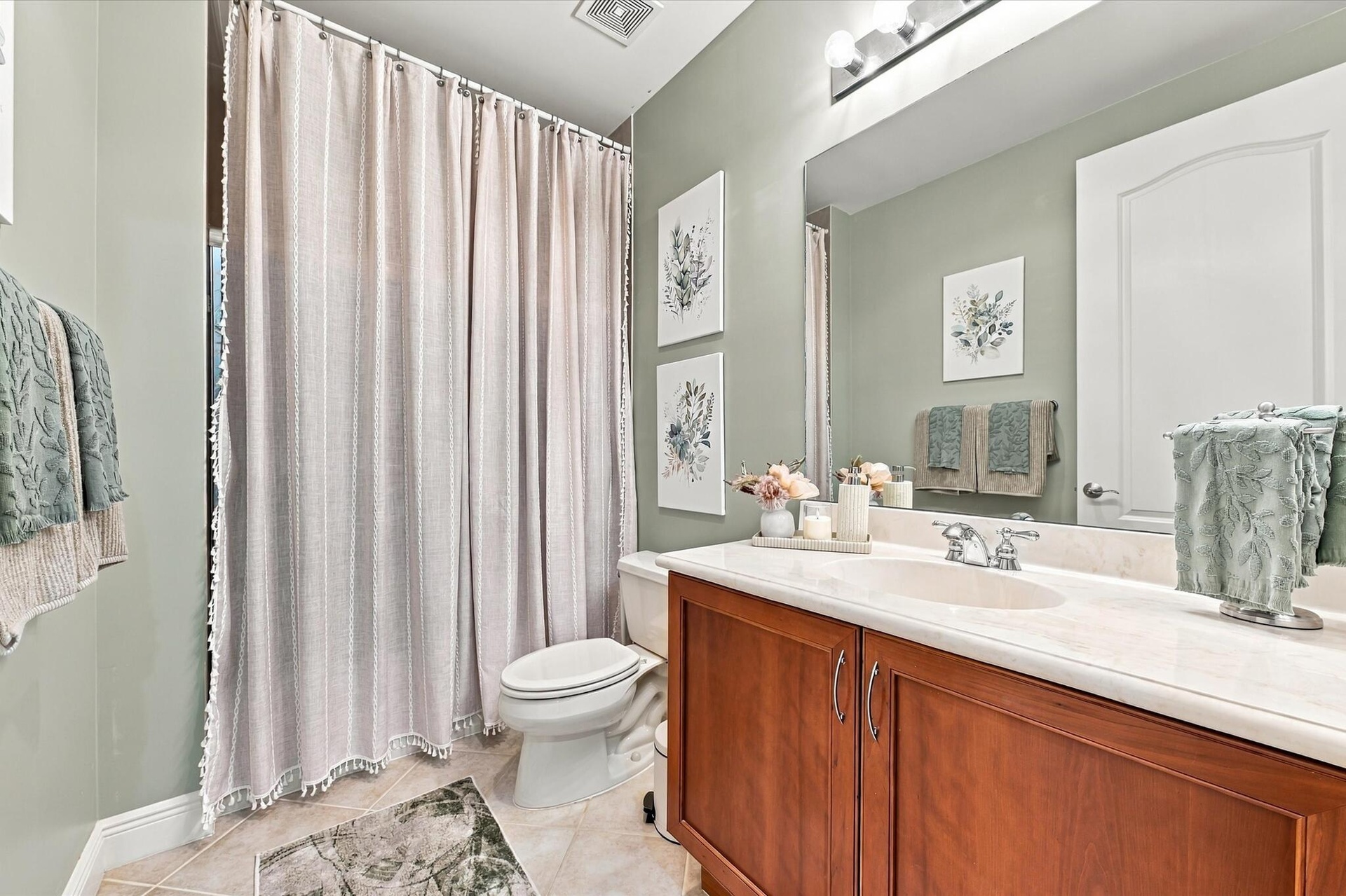 Full bathroom featuring a wood-finish vanity with a light-toned solid surface countertop, an integrated oval basin, a large wall-mounted mirror, and t