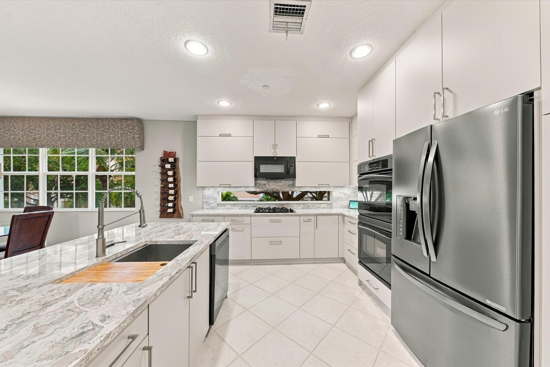 Kitchen featuring flat-panel cabinetry, stone countertops, a stainless steel double wall oven, a stainless steel refrigerator, and recessed lighting