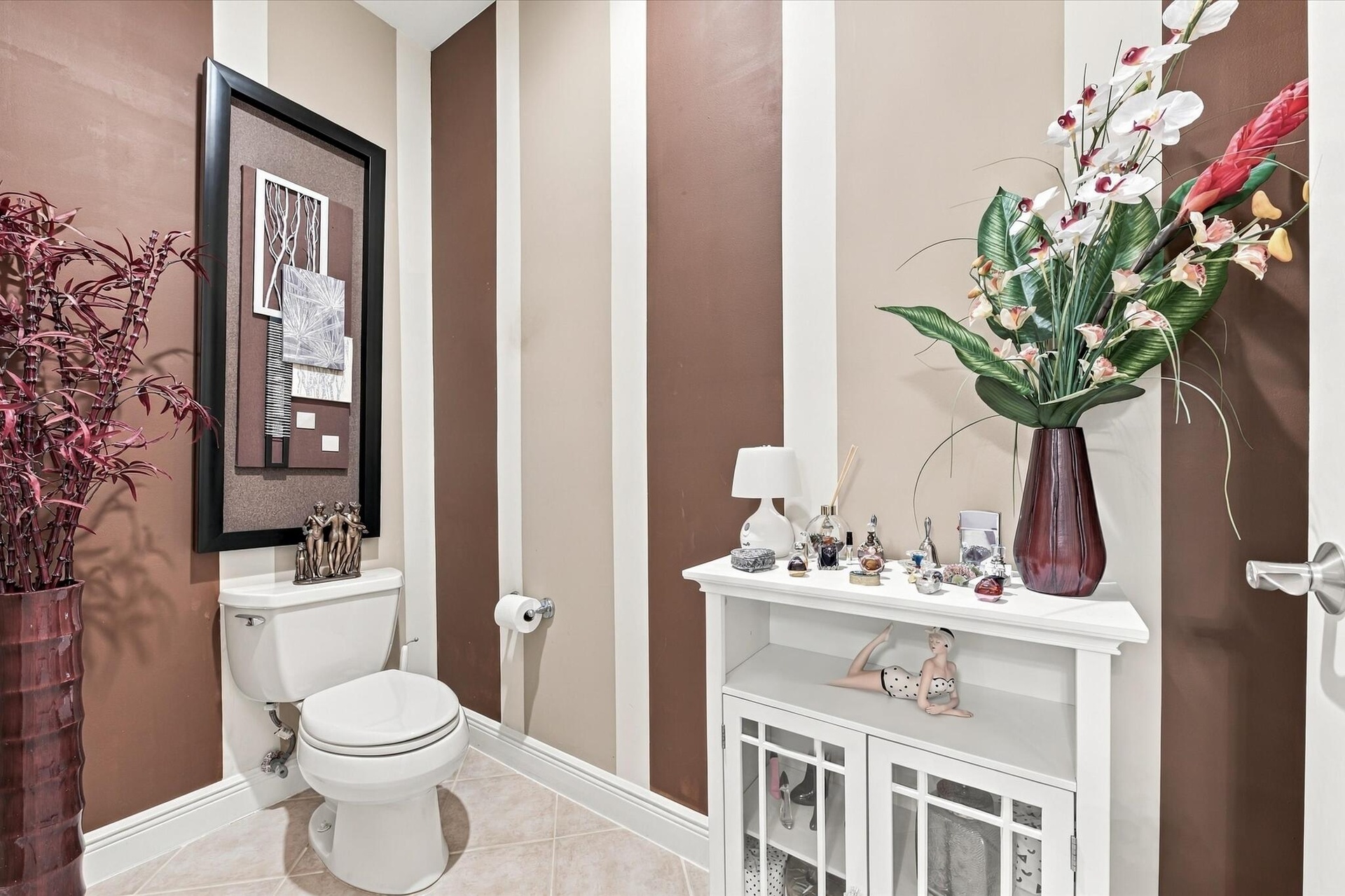 Restroom featuring two-tone striped wall detailing, ceramic tile flooring, and a standard-profile toilet