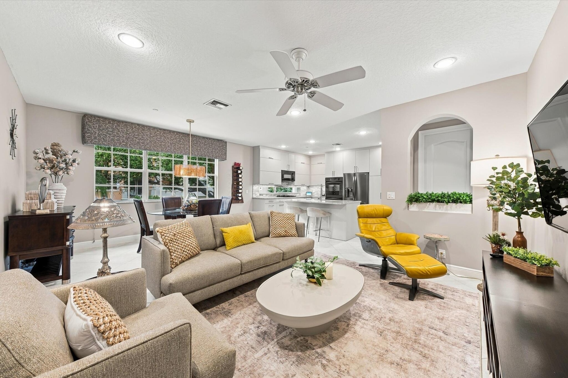Open-concept interior featuring recessed lighting, a ceiling fan, a kitchen island with stone countertops, white flat-panel cabinetry, and an arched w