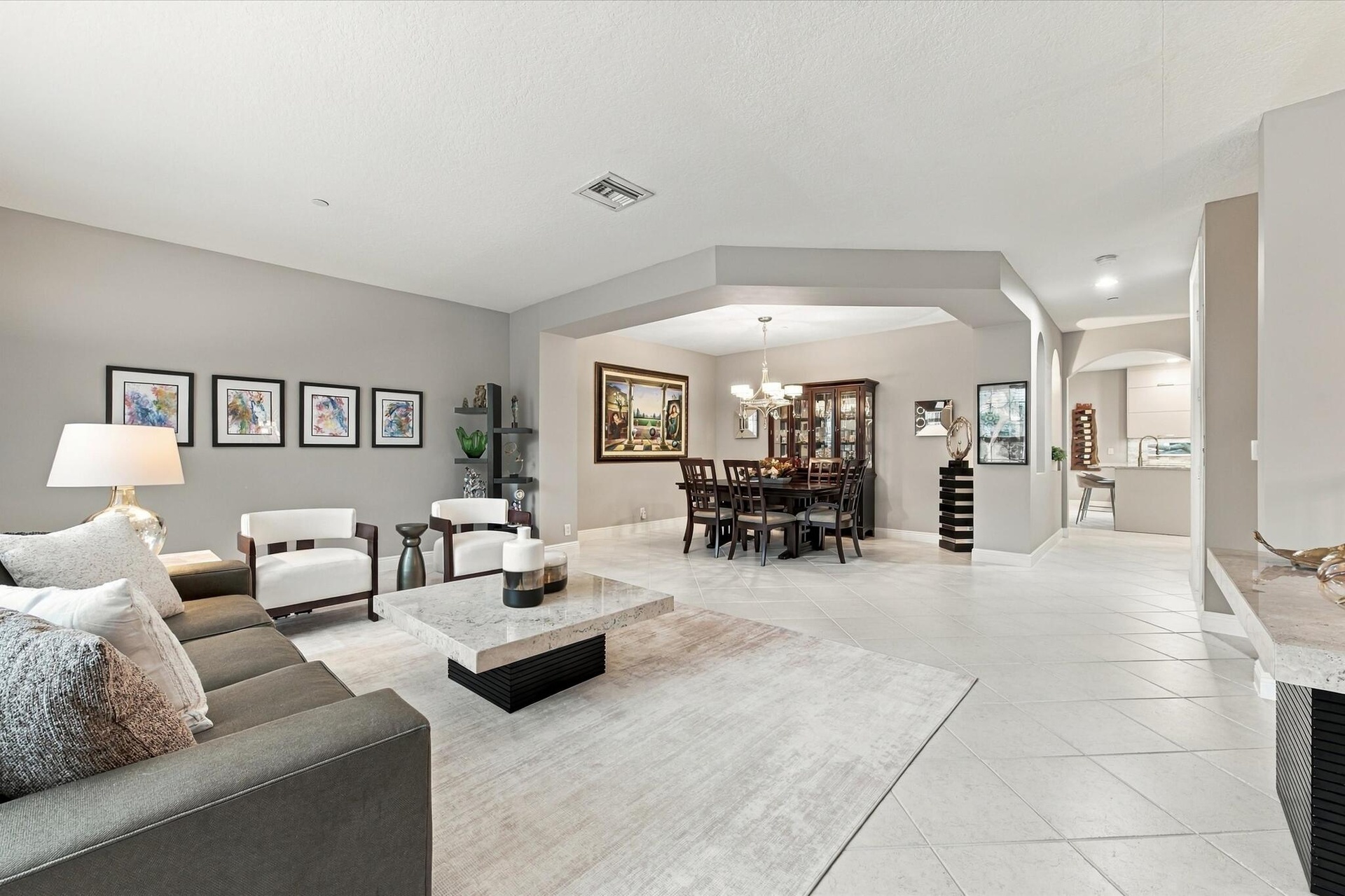 Living area featuring neutral wall tones, large-format tile flooring, recessed lighting, and a distinct architectural recessed ceiling detail