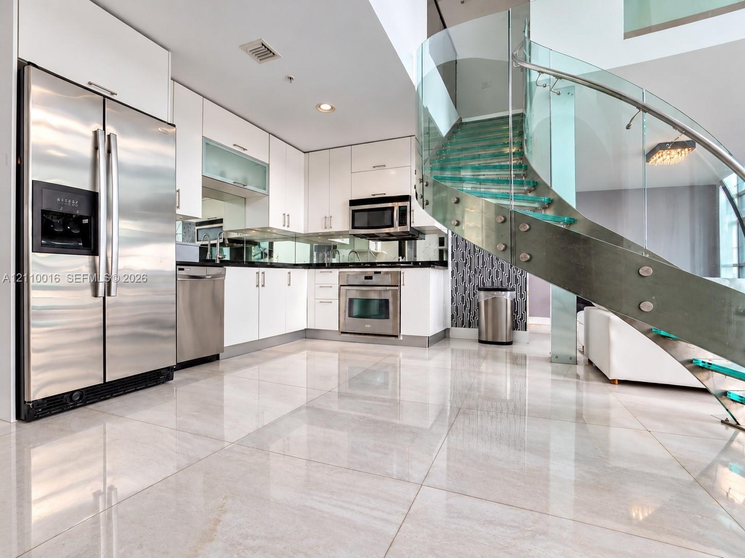 Spiral staircase featuring glass treads and stainless steel railings, double-height ceilings, polished tile flooring, floor-to-ceiling windows, and fr