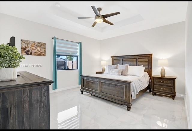 Tray ceiling featuring a central multi-blade ceiling fan with integrated lighting and polished, light-toned tile flooring