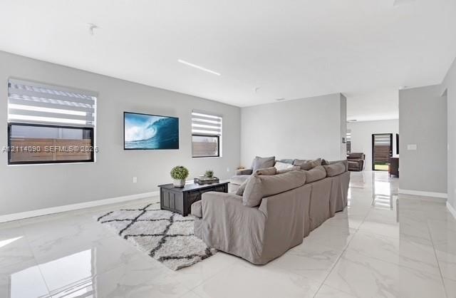 Neutral-toned interior featuring large-format tile flooring, recessed ceiling lighting, and windows equipped with dual-shade treatments