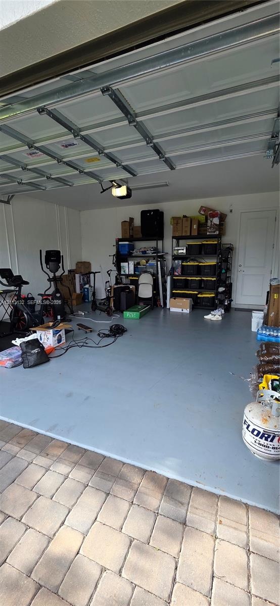 Garage featuring painted concrete flooring, a sectional overhead door, and a dedicated service door