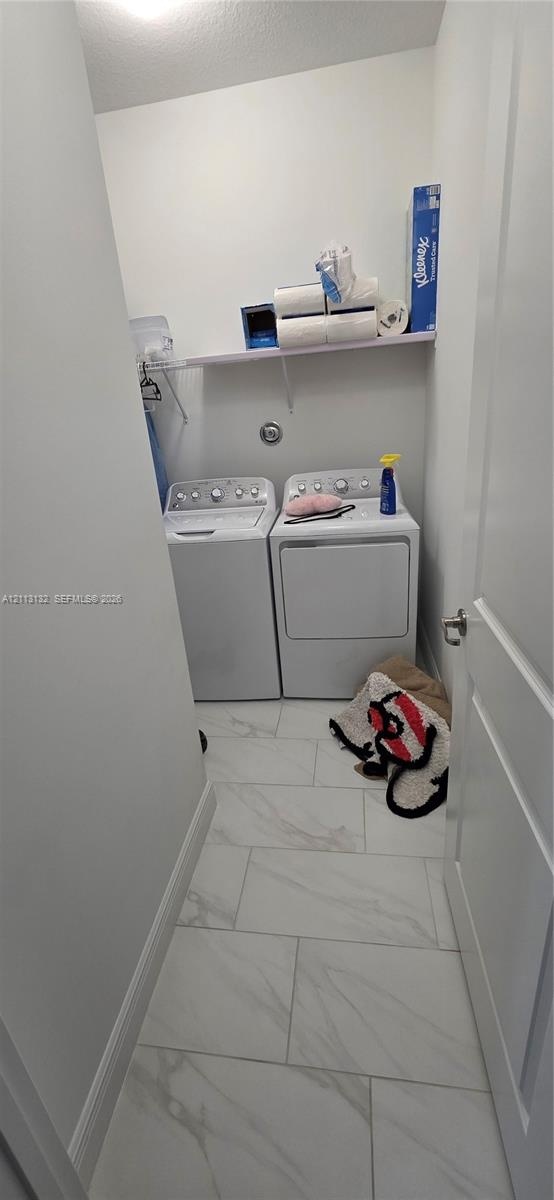 Dedicated laundry alcove featuring large-format stone-patterned tile flooring and an integrated wall-mounted shelf