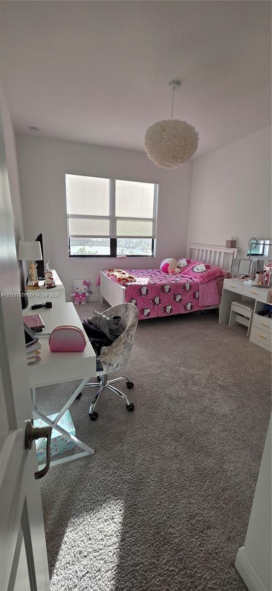 Interior space featuring neutral-toned carpeting, high ceilings, a window with roller shades, and a spherical textured ceiling fixture
