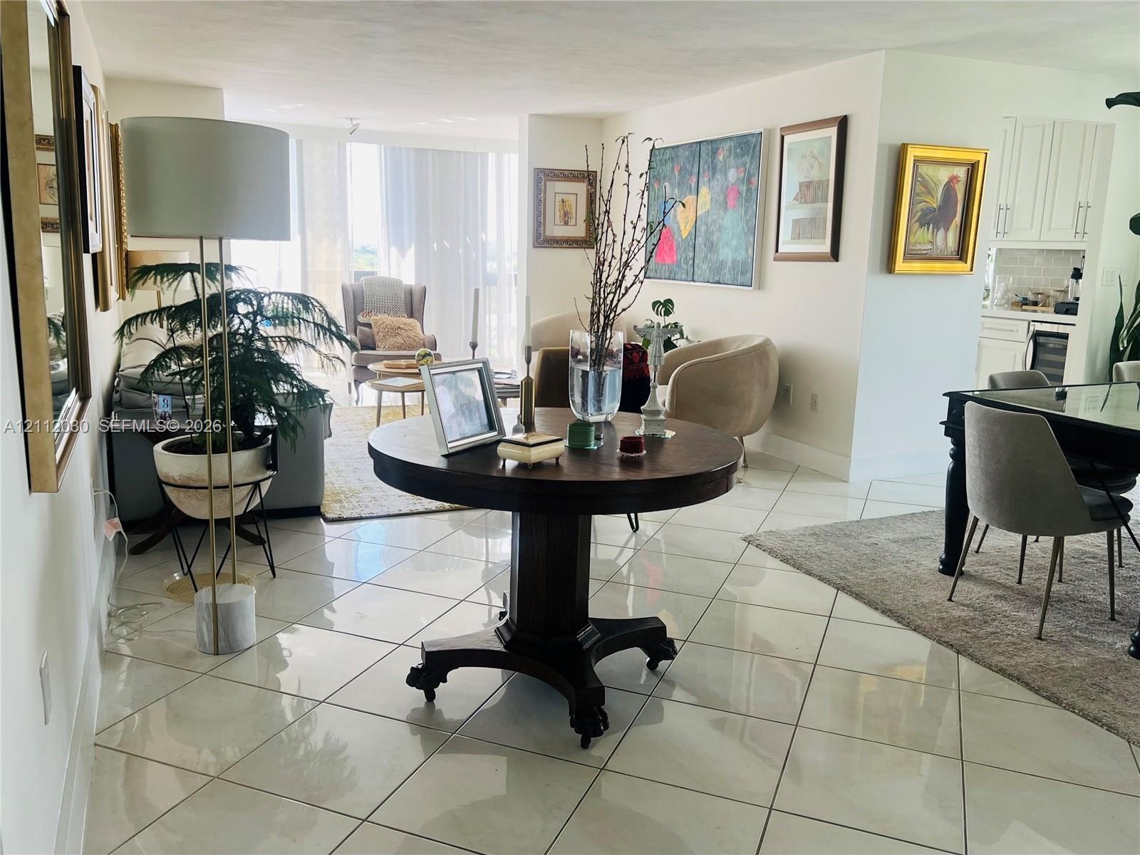 Polished tile flooring, expansive floor-to-ceiling windows, and white shaker-style kitchen cabinetry