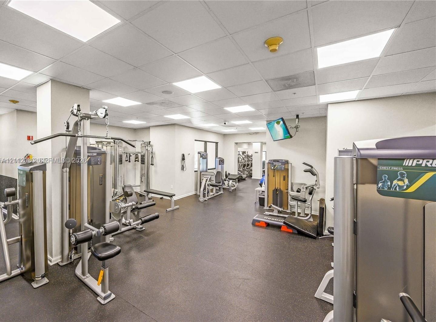 Fitness room featuring a drop ceiling with integrated recessed lighting and durable flooring