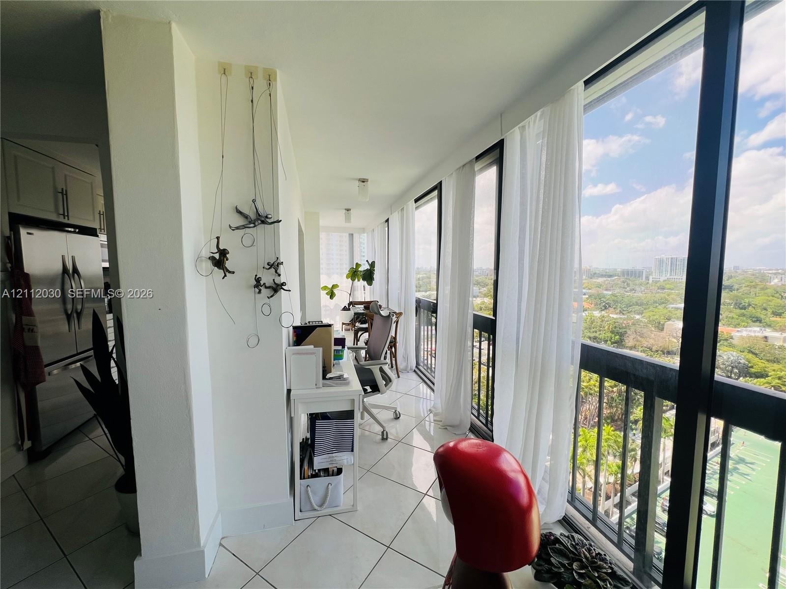 Floor-to-ceiling windows, tile flooring, and stainless steel kitchen appliance