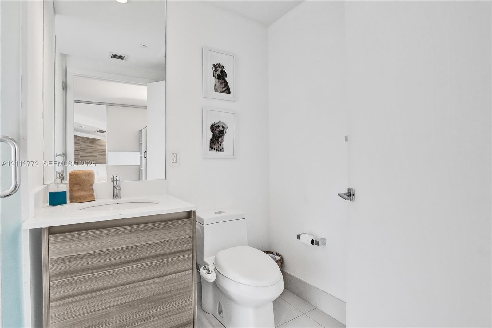 Bathroom featuring a floating wood-finish vanity, integrated white countertop with a recessed basin, chrome single-lever faucet, and large-format wall
