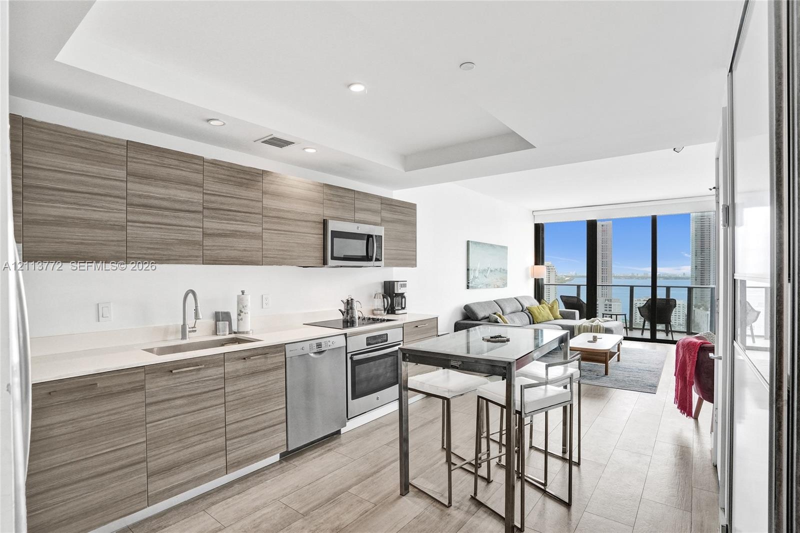 Kitchen featuring horizontal wood-grain cabinetry, stainless steel appliances, recessed ceiling lighting, and wood-finish flooring with floor-to-ceili