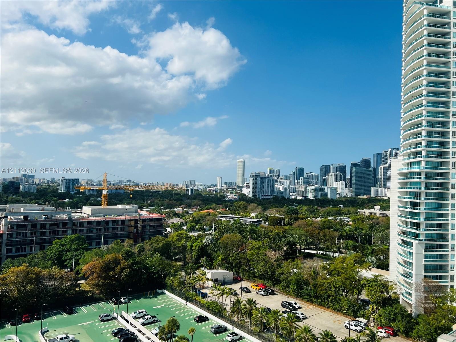 High-rise residential tower featuring floor-to-ceiling glass paneling, wraparound balconies, and expansive urban skyline scenery