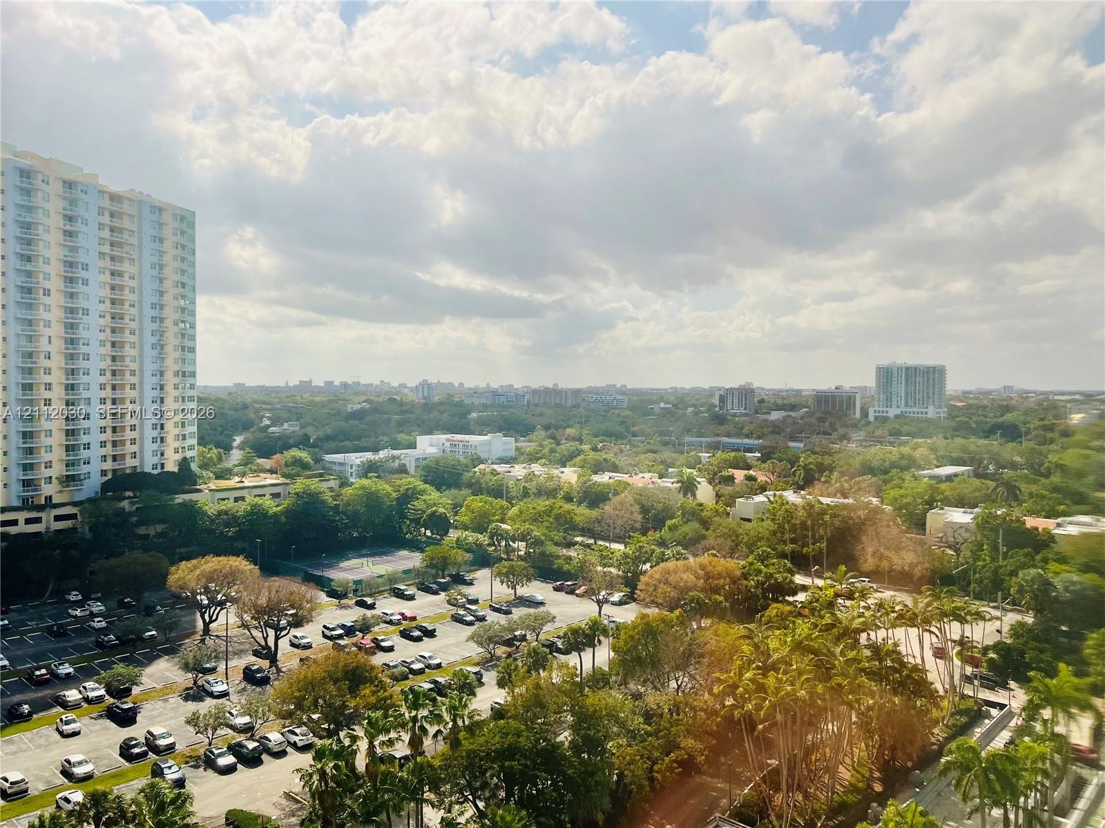 Elevated cityscape featuring expansive tree canopy, high-rise architectural silhouettes, and integrated surface parking