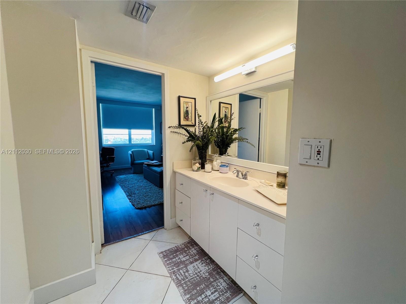 Vanity featuring a solid-surface countertop, integrated oval sink, chrome dual-handle faucet, white cabinetry with crystal-style hardware, and a full-