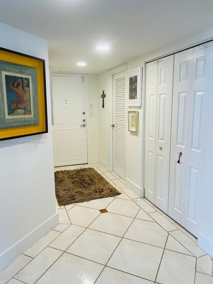 Entryway featuring tile flooring with decorative stone inlays, recessed lighting, louvered closet doors, and multi-panel interior doors