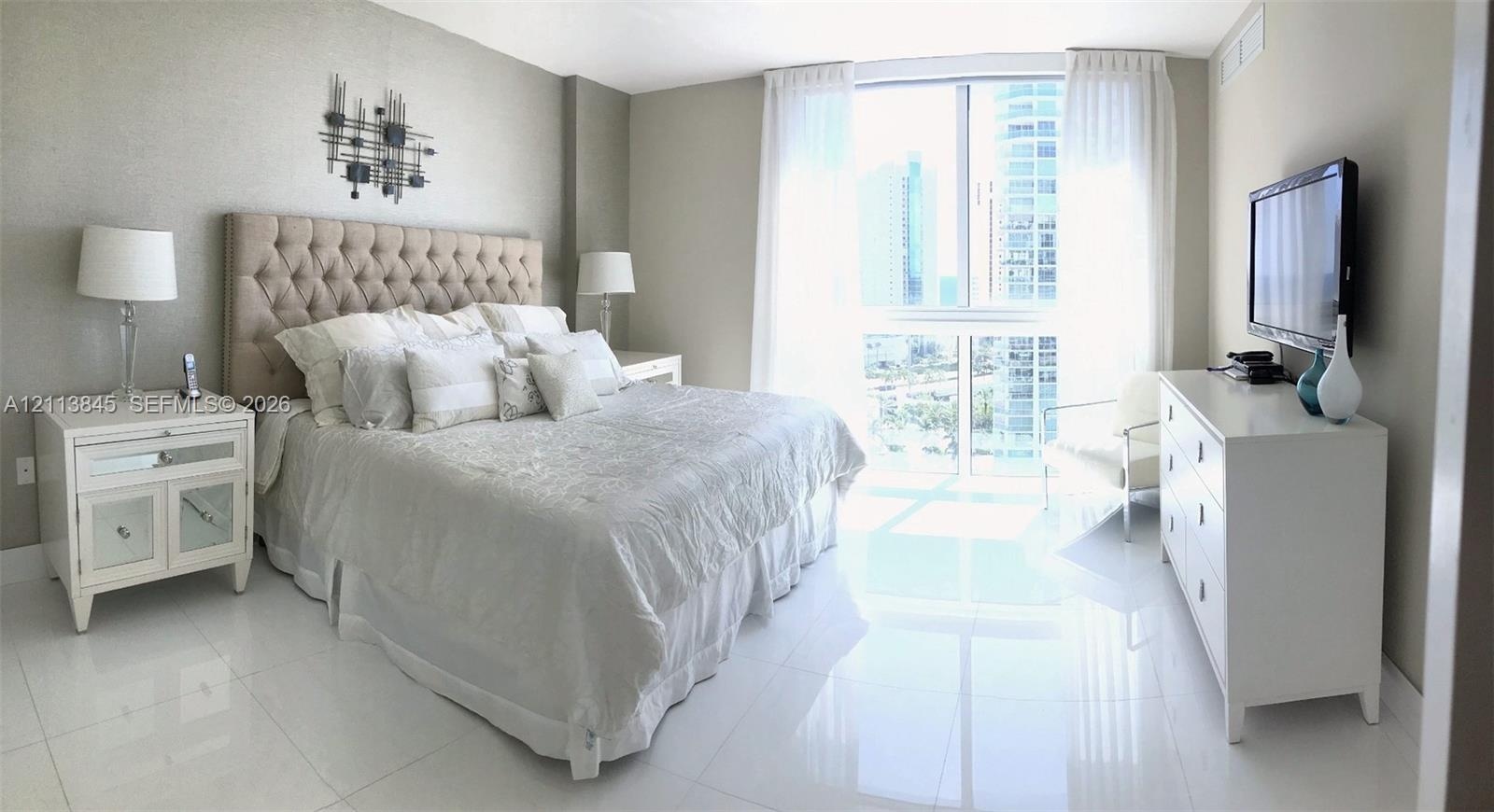 Floor-to-ceiling windows featuring urban scenery, complemented by polished light-toned tile flooring throughout