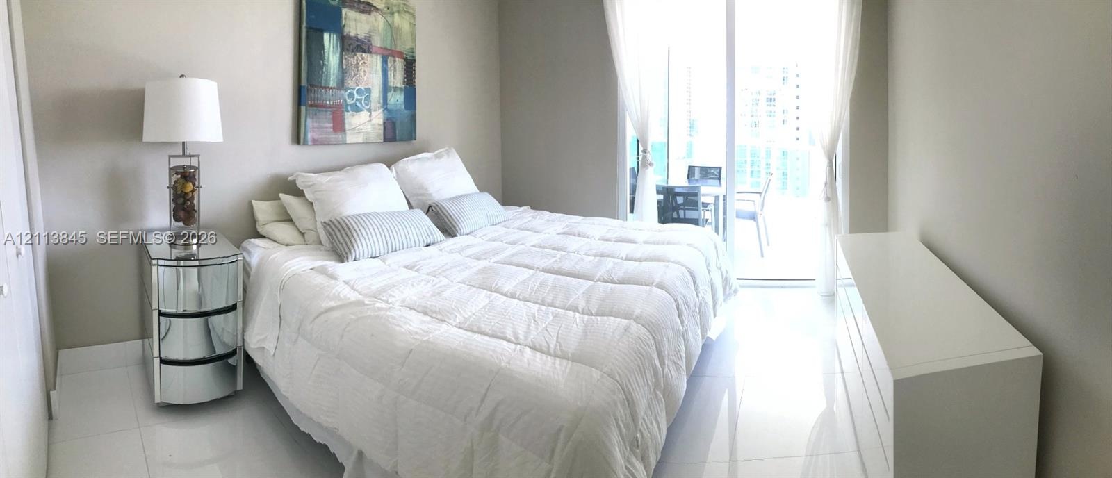 Spacious interior featuring white tile flooring, neutral wall tones, and glass sliding doors providing external access